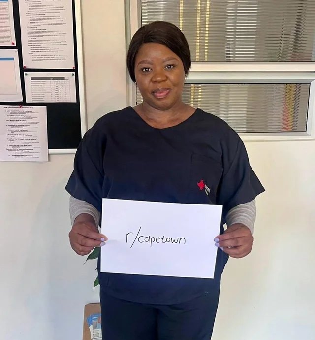 Sister Lindiwe, Registered Nurse, inside the Epicentre walk-in lab in Observatory, holding a card reading r/capetown